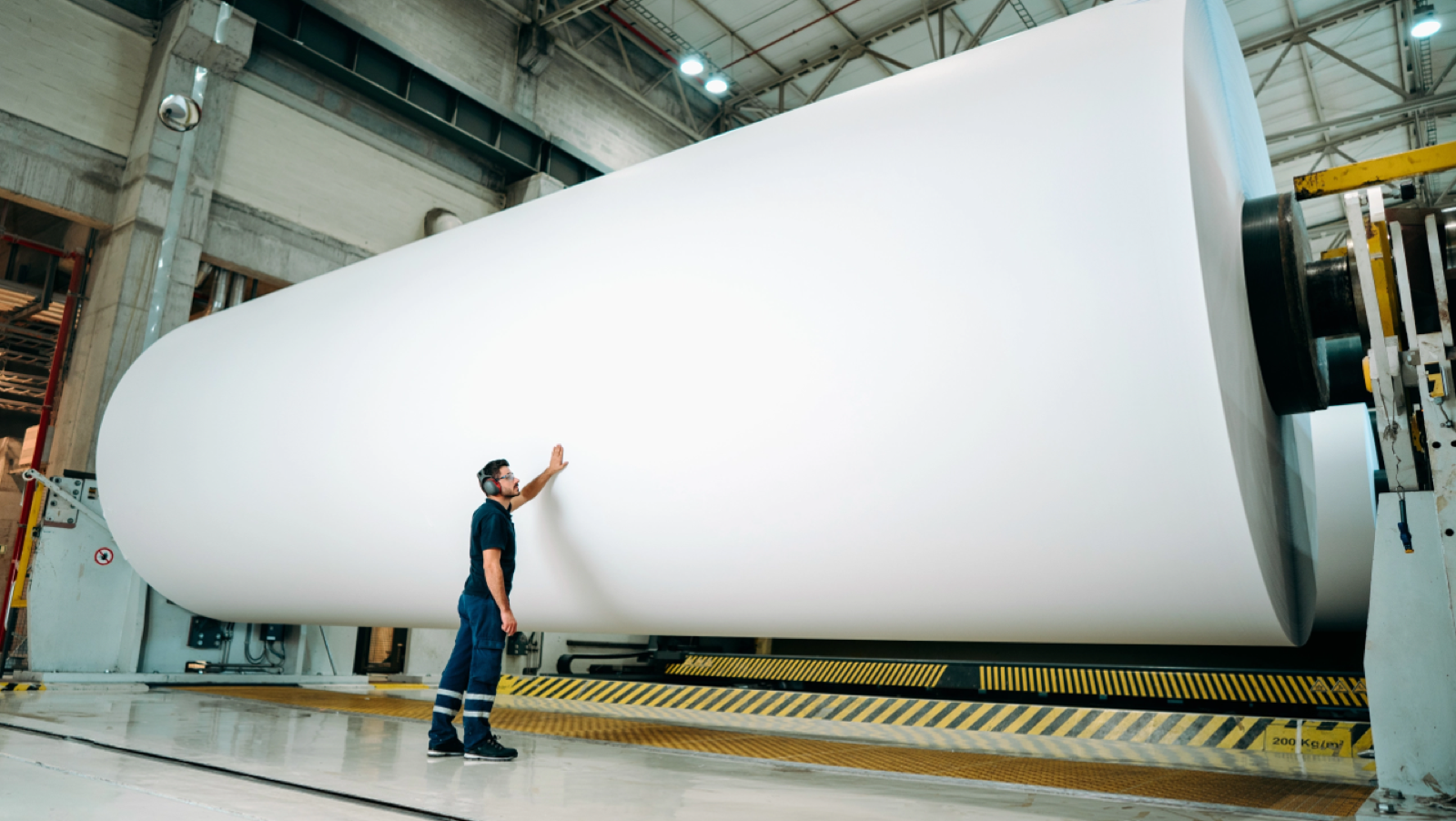 Operator inspecting a large paper machine roll